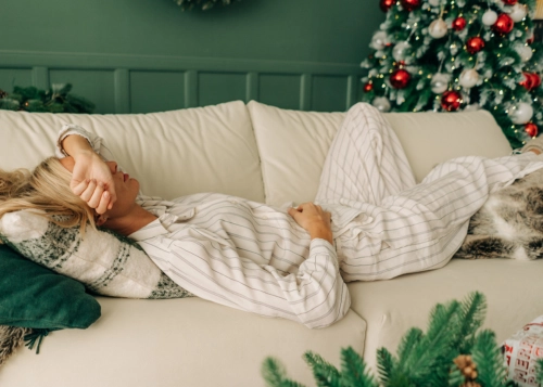 A woman experiencing christmas burnout, laying on the sofa
