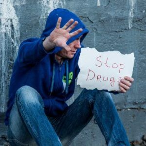 a man holding a sign that states 'stop drugs'