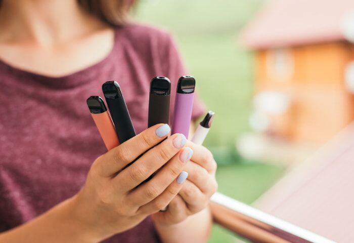 Are Disposable Vapes Dangerous? A woman holding many different disposable e-cigarettes in her hands.