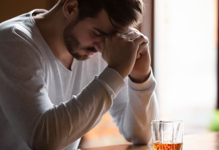 Warning Signs of Alcohol Abuse - an image of a man sitting on bar counter looking deflated drinking alcohol drink
