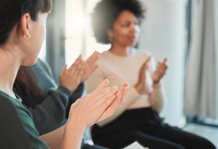Addiction cycle of change. An image of people clapping to show support within a group therapy session environment.